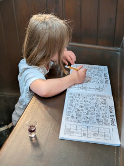 Young child fills in a 'look and find' sheet in church, with a communion cup alongside