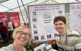 Two smiling faces wearing rainbow lanyards stand in front of a map showing the location of inclusive churches in Bristol