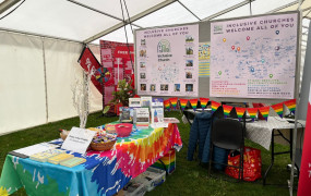 A rainbow cloth covered table with flyers, chocolate and information about local inclusive churches